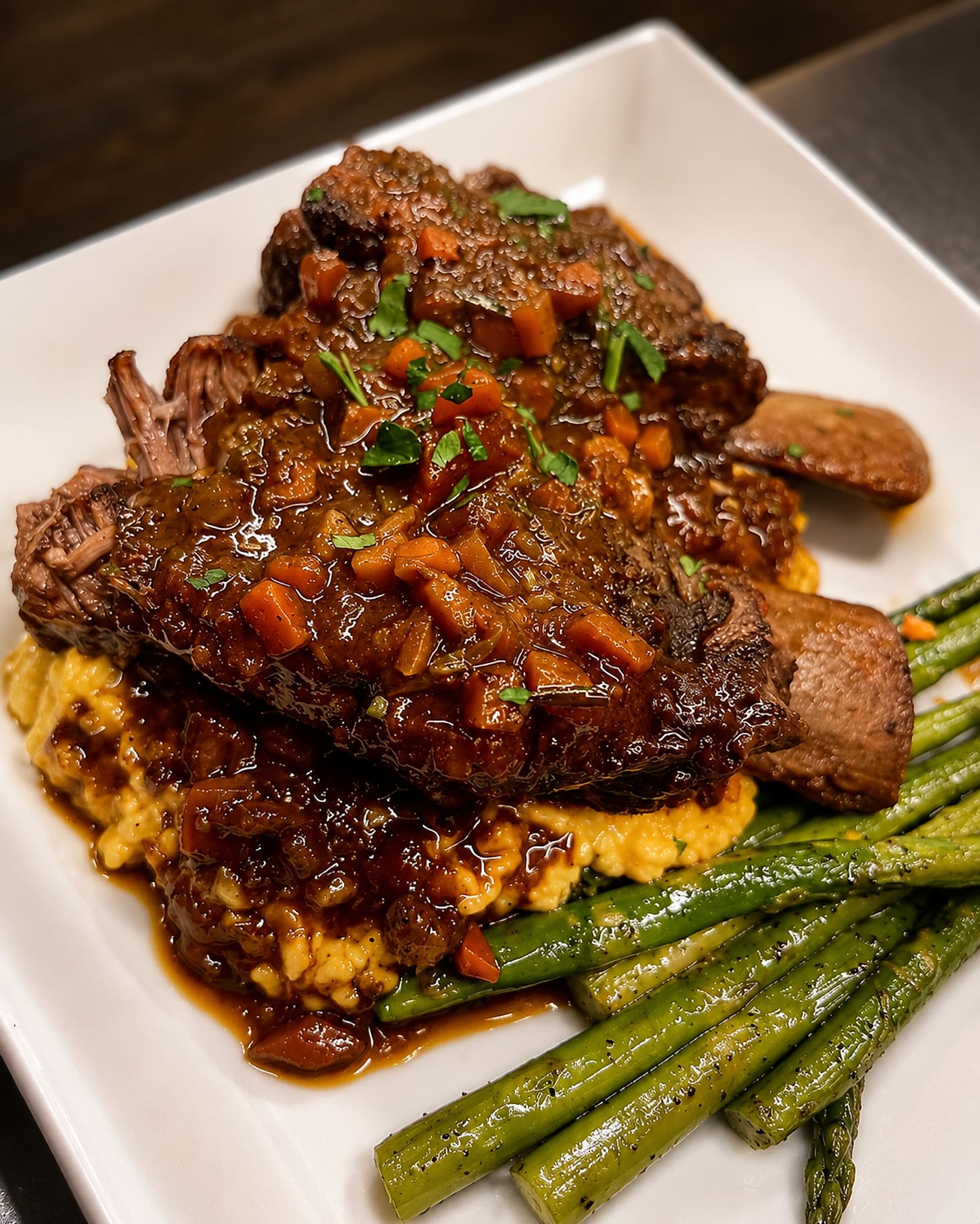 A braised short rib in its own gravy over soft polenta, with asparagus alongside.